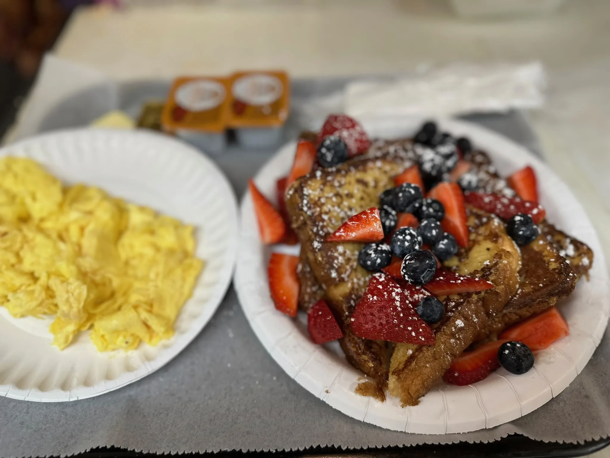Challah French Toast piled with fresh strawberries and blueberries, dusted with powdered sugar