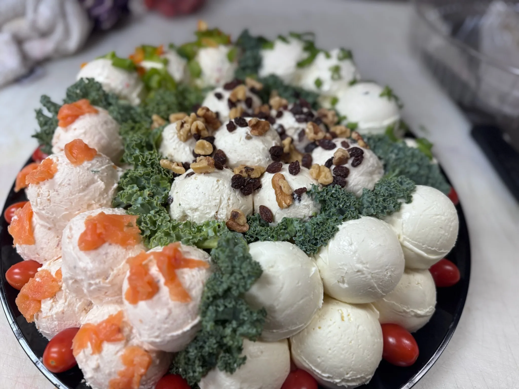 Hand-scooped cream cheese balls — plain, vegetable, walnut-raisin, and salmon — arranged with fresh garnishes