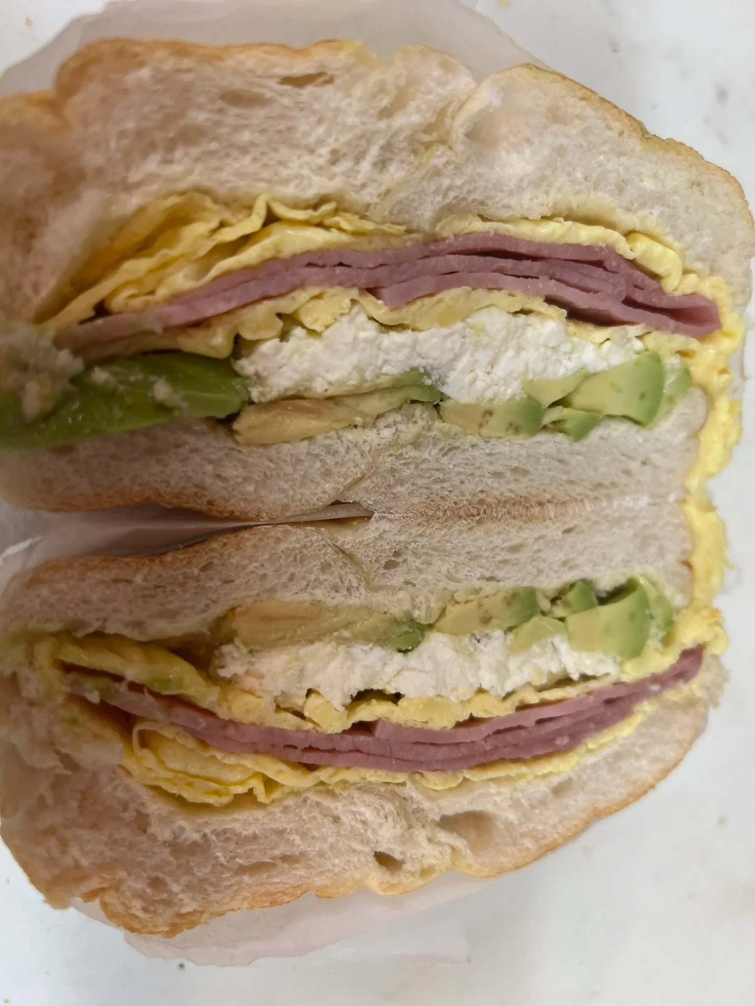 Egg, ham, and fresh avocado layered on a sliced bagel