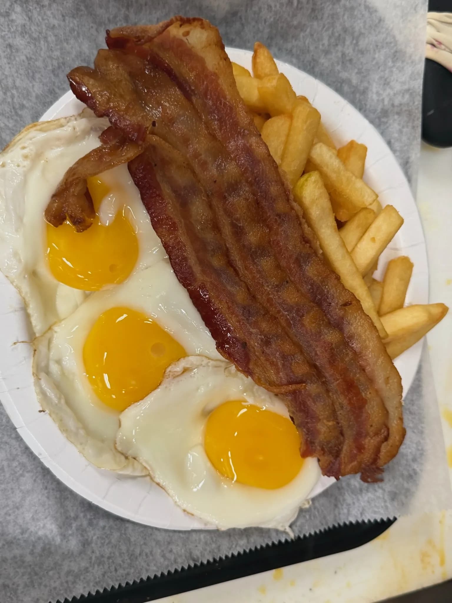 Three eggs over easy with crispy bacon and a heap of golden home fries