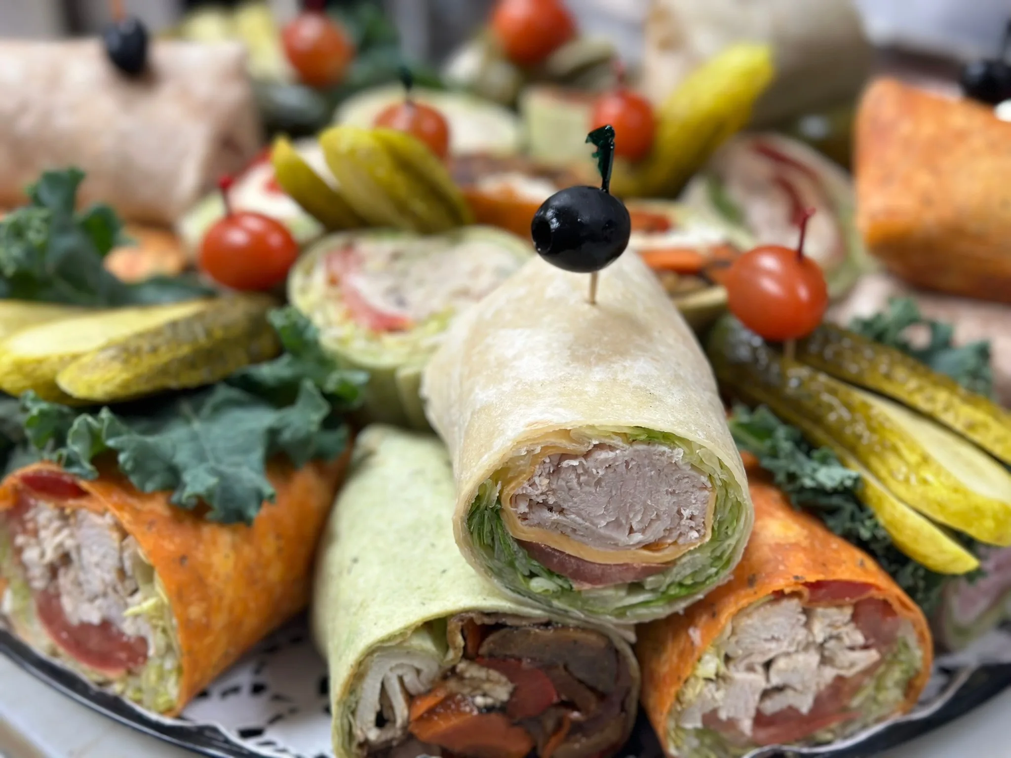 Elegant Wrap Platter — wraps fanned across a tray with pickles, kale, and cherry tomato picks
