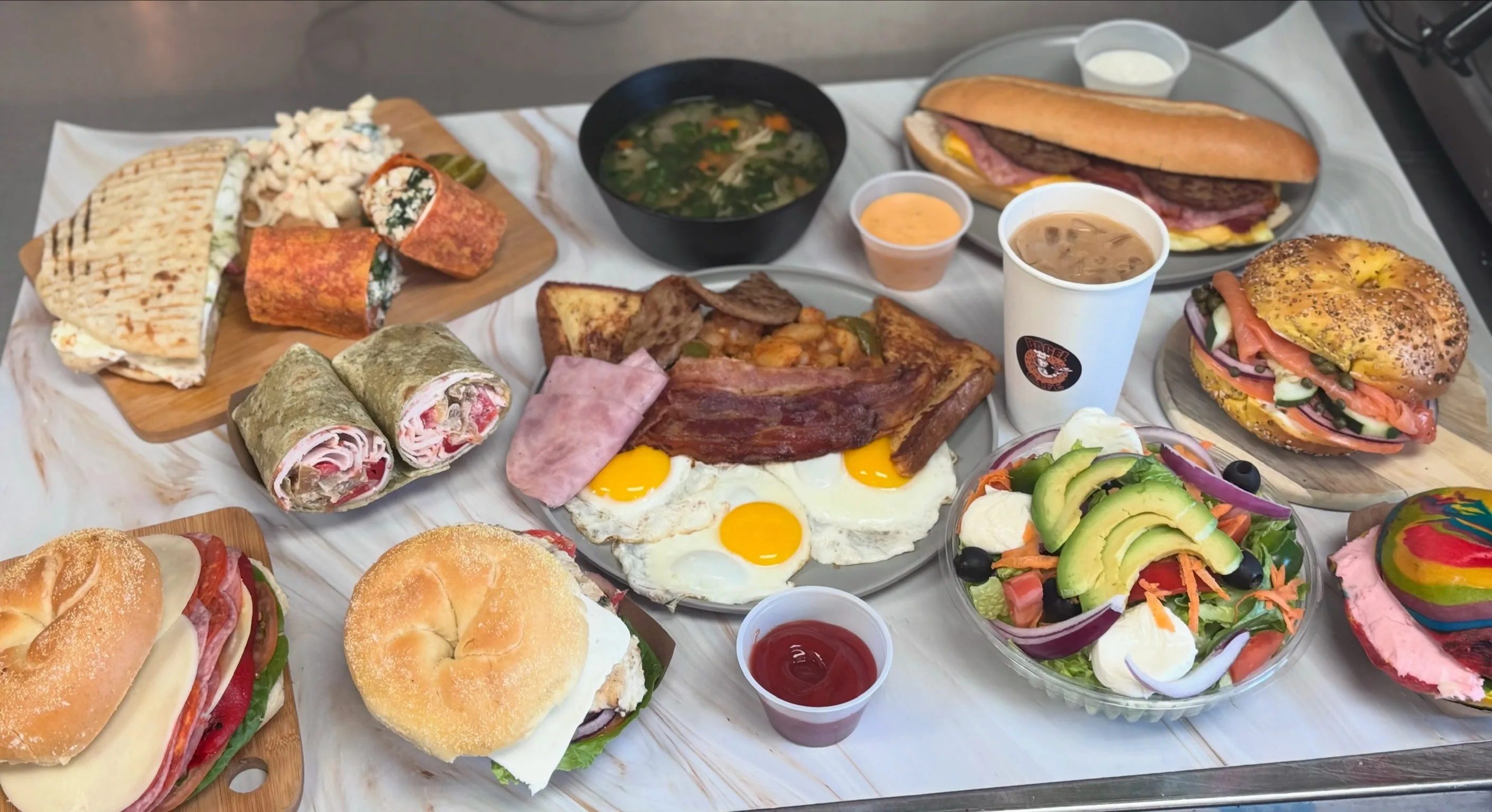 Our full menu spread — bagels, wraps, eggs, salads, heroes, and coffee