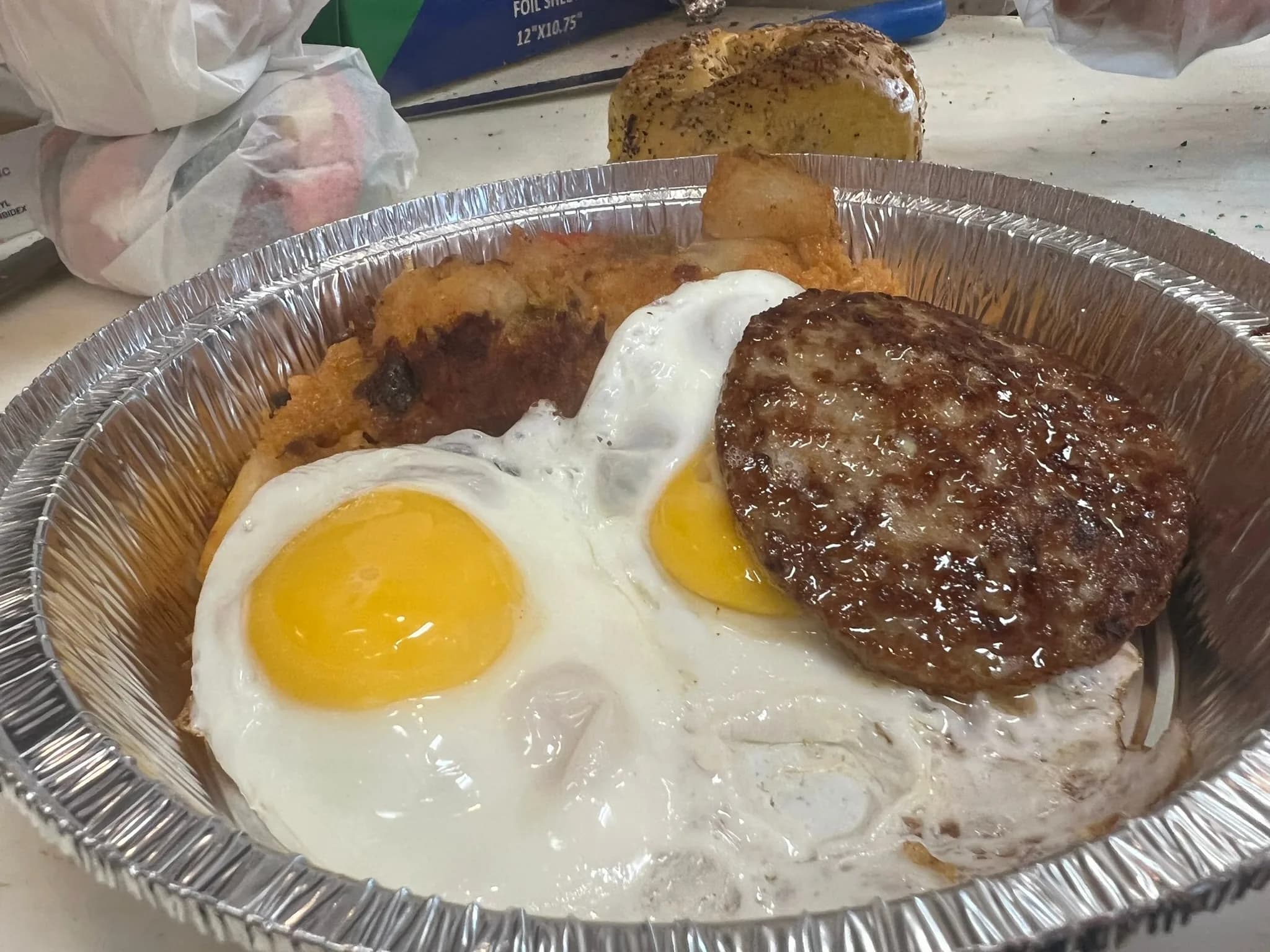 Two sunny-side eggs with a juicy sausage patty and house home fries