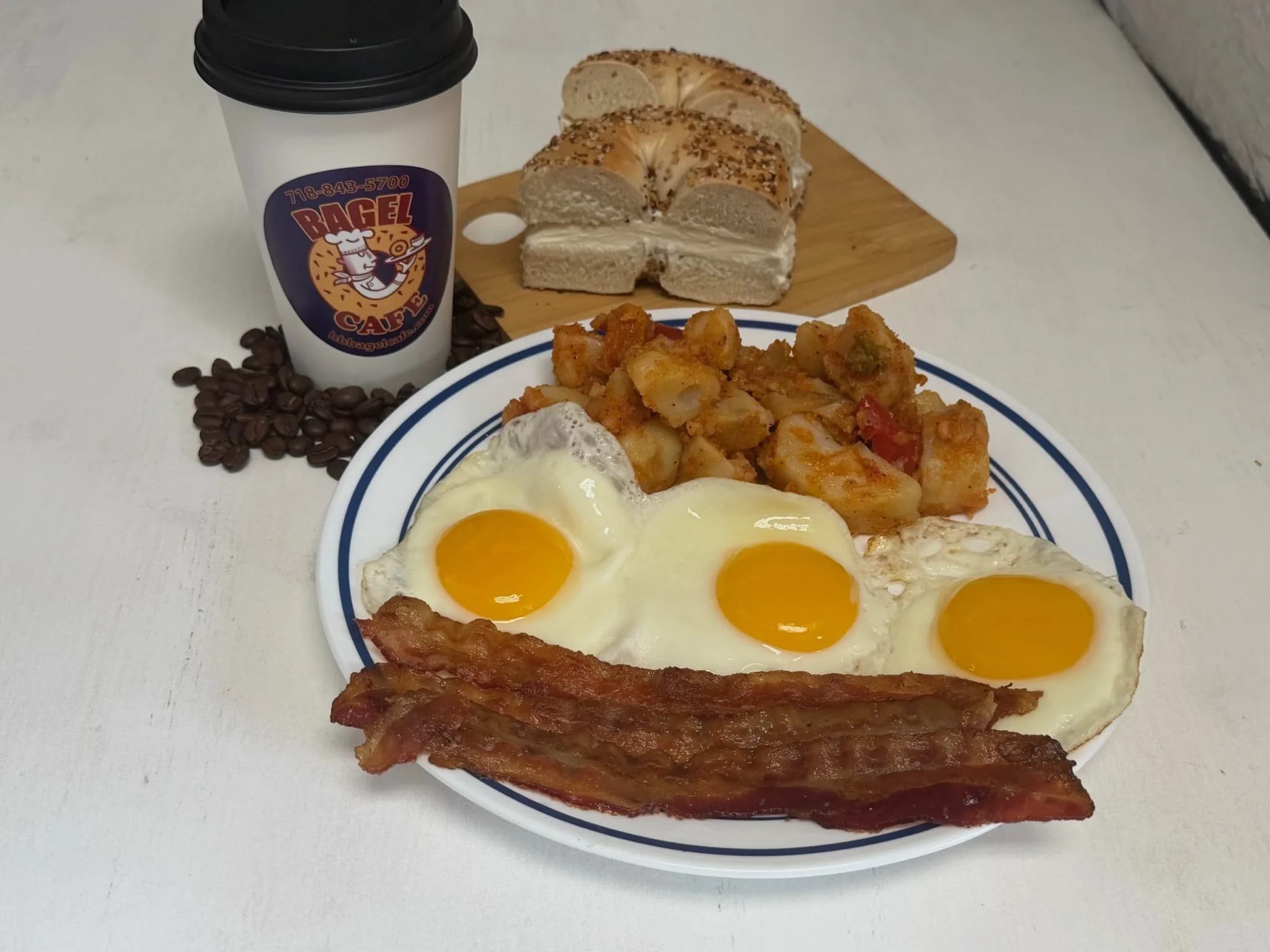 Three eggs, bacon, home fries, and an everything bagel with cream cheese — the full plate, with coffee on the side